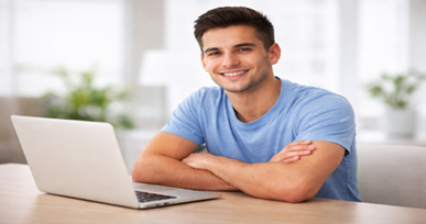 Smiling student sitting at a table with a laptop, ready to study or work online