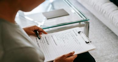 Person holding a clipboard and pen while reviewing or filling out a questionnaire form.
